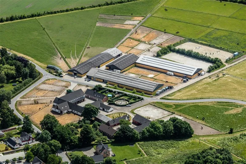 Luftfoto af Kirstinelund Ridecenter med ridehaller, stalde og folde